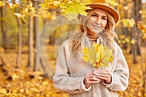 Happy caucasian woman posing at camera with yellow autumn leave in hands