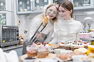 happy Caucasian Young Mother and Teenage Daughter looking at fresh baked delicious homemade croissants in kitchen