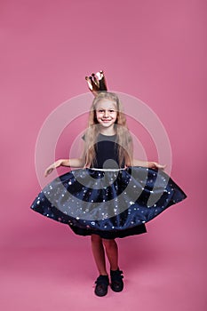 Happy celebration of birthday party. little girl in princess dress and crown on pink background