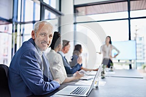 Happy CEO, boss or chairman looking confident in a team meeting at work. Portrait of a proud employee with colleagues as
