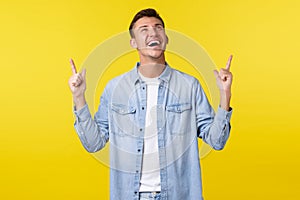 Happy charismatic blond guy laughing out loud and smiling white teeth, looking and pointing fingers up at funny
