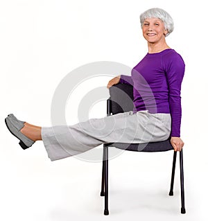 Happy charming beautiful elderly woman doing exercises at home on a chair. Workout gymnastics for health. On a white background