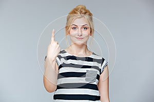 Happy charming young woman showing one finger and pointing up