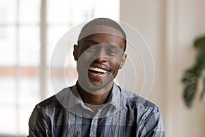 Happy cheerful african millennial man looking at camera at home