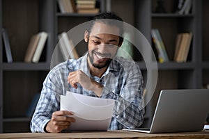 Happy cheerful African student guy reading admission letter from school