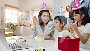 Happy cheerful Asian family having fun celebrating birthday with parents and grandparents on video call at home. Spending time