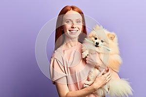 Happy cheerful beautiful girl holding a dog with a toothbrush on its teeth