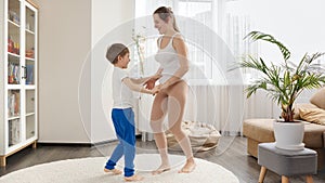 Happy cheerful boy dancing with his mother at home and having fun together. Family having fun together, listening music, active