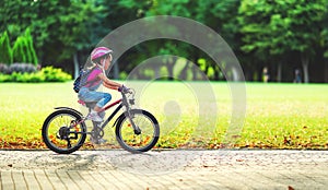 Happy cheerful child girl riding a bike in Park in nature