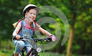 Happy cheerful child girl riding a bike in Park in nature