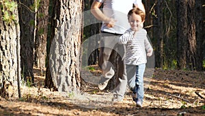 A happy cheerful child runs among the trees in a forest or Park. A father plays with his son in the open air, catching