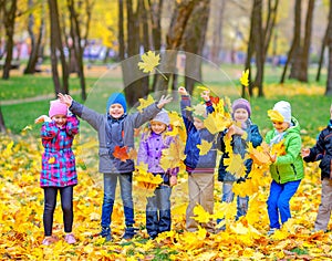 Happy cheerful children play toss foliage in autumn park