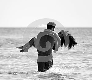 Happy cheerful couple having fun hugging running in the sea together. Romantic vacation, honeymoon love