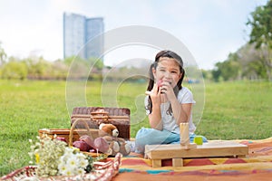 Happy cheerful cute girls eat apple with picnic set at outdoors park