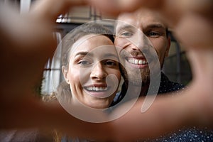 Happy cheerful dating couple portrait through hand heart shaped frame