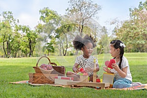 Happy cheerful ethnic girls play wooden block puzzle together at outdoors park , Relationship little kids, Diverse black and white