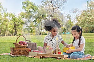 Happy cheerful ethnic girls play wooden block puzzle together at outdoors park , Relationship little kids, Diverse ethnic concept