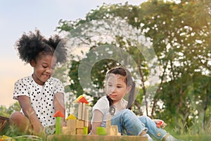 Happy cheerful ethnic girls play wooden block puzzle together at outdoors park , Relationship little kids, Diverse ethnic concept