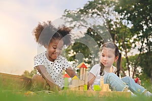 Happy cheerful ethnic girls play wooden block puzzle together at outdoors park , Relationship little kids, Diverse ethnic concept