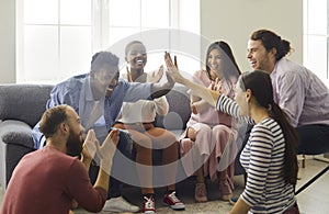 Happy cheerful excited young diverse friends giving each other a high five and laughing