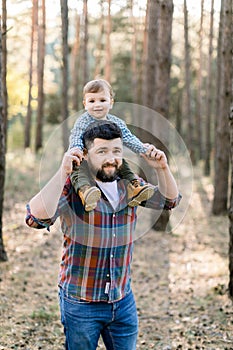Happy cheerful family, handsome bearded father and his little cute baby son in the autumn park, playing and laughing