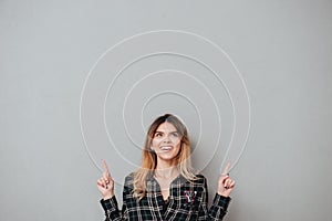 Happy cheerful girl pointing two fingers up at copy space