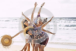 Happy cheerful group of young people friends having fun together in friendship at the beach with sea in background - tourism