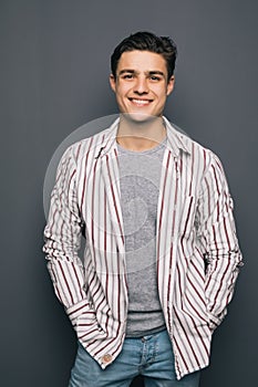 Happy cheerful guy with crossed hands on gray background