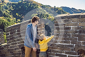 Happy cheerful joyful tourists dad and son at Great Wall of China having fun on travel smiling laughing and dancing