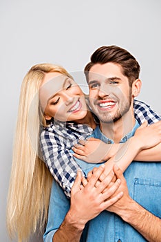 Happy cheerful man carrying his girlfriend on the back and she hug him