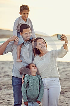 Happy cheerful mixed race family smiling for a selfie spending time at the beach together. Hispanic mother smiling