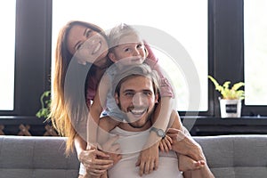 Happy cheerful parents having fun with cute children daughters playing on sofa