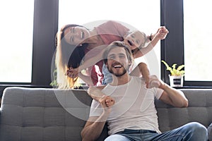 Happy cheerful parents having fun with cute children daughters playing on sofa