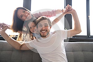 Happy cheerful parents having fun with cute children daughters playing on sofa