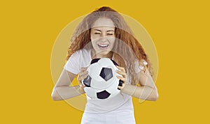 Happy cheerful pretty young woman or teenage girl holding soccer ball and laughing