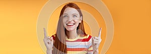 Happy cheerful redhead girl having fun amusement park laughing joyfully pointing look up index fingers upwards enjoy