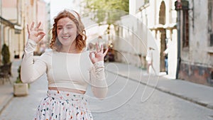 Happy cheerful redhead woman showing ok gesture positive like sign approve something good celebrate