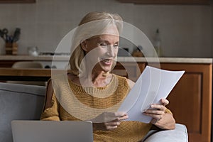 Happy cheerful senior homeowner woman reading paper document