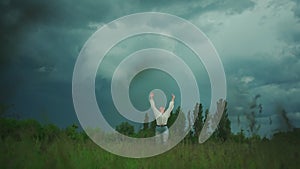 Happy cheerful senior woman dance and spinning around in field at cloudy weather