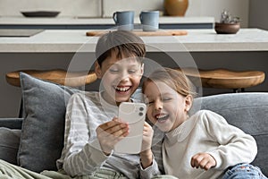 Happy cheerful sibling kids watching funny media on smartphone