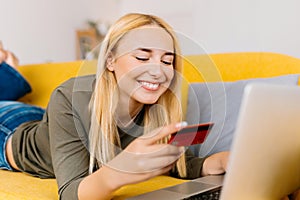 Happy cheerful smiling young blonde woman doing online shopping