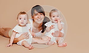 Happy cheerful smiling young mother holding baby on brown background