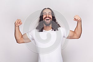 Happy cheerful strong bodybuilder man standing showing his biceps and triceps.