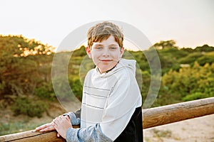 Happy cheerful teenager standing on beach at sunset. happy preteen boy smiling at the camera. Kid on family vacation at