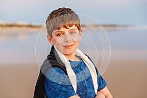 Happy cheerful teenager standing on beach at sunset. happy preteen boy smiling at the camera. Kid on family vacation at