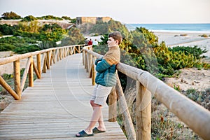 Happy cheerful teenager standing on beach at sunset. happy preteen handsome boy smiling at the camera. Kid on family