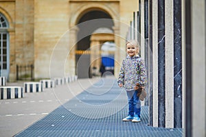 Happy cheerful toddler girl running within Columns of Buren in Palais-Royale, Paris
