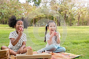 Happy cheerful white girls and black girl eat apple together at outdoors park , Relationship little kids, Diverse ethnic concept