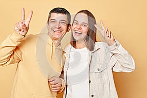 Happy cheerful woman and man wearing casual style clothing standing isolated over beige background looking smiling to camera,