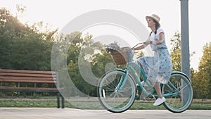 Happy cheerful woman is riding vintage bike and enjoying outdoor leisure activity in summer. Charming girl with healthy and active